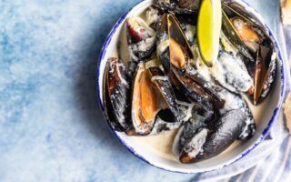 Blue mussels in wine sauce with lime and bread. Stew mussels in wine, leek and blue cheese. Seafood