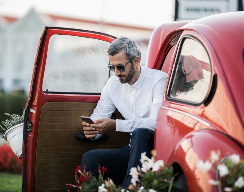 The man writes sms in the red oldtimer