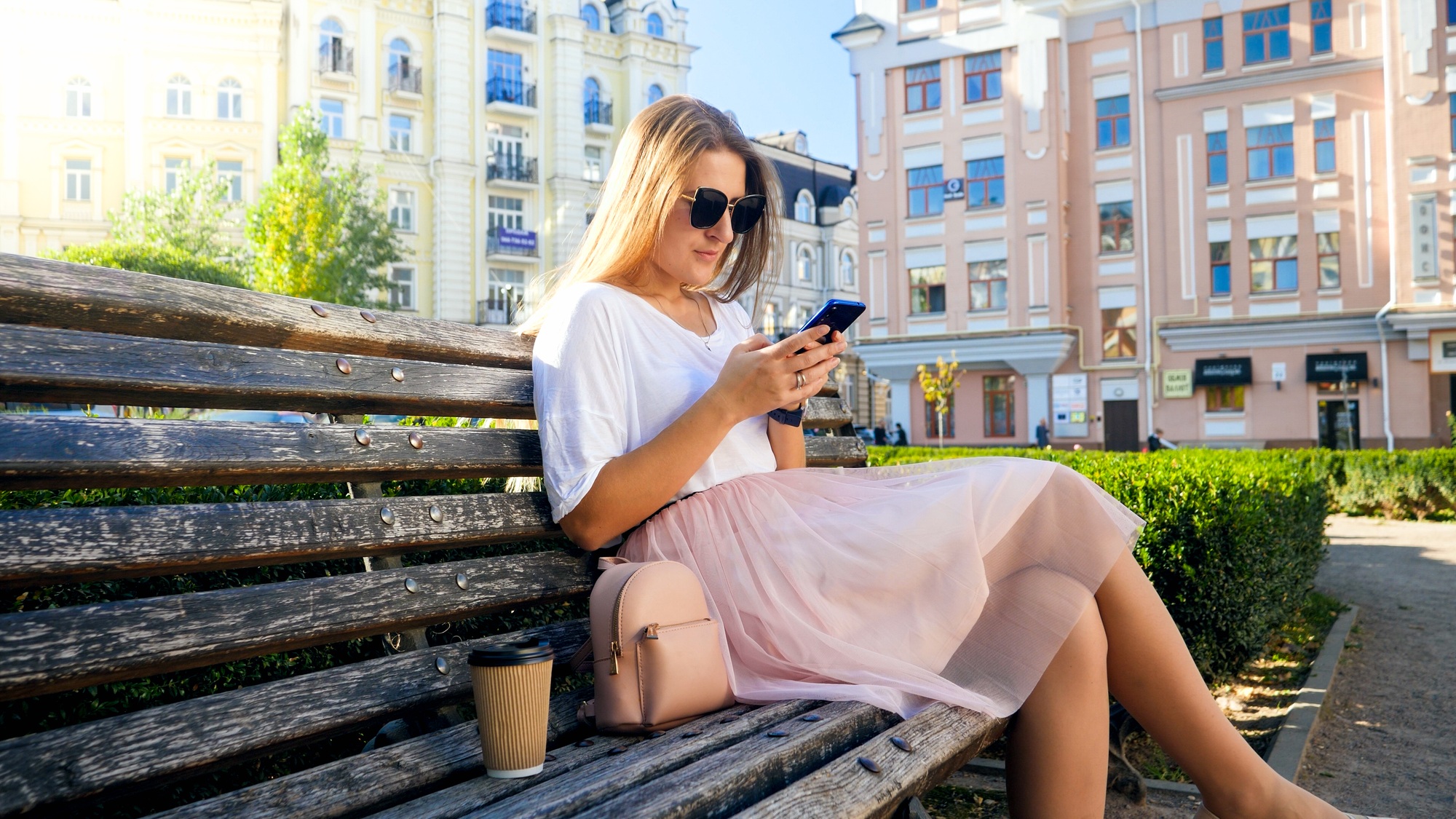 Beautiful sexy woman sitting on bench and using smartphone