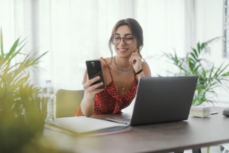 Young woman sitting at desk and using her smartphone