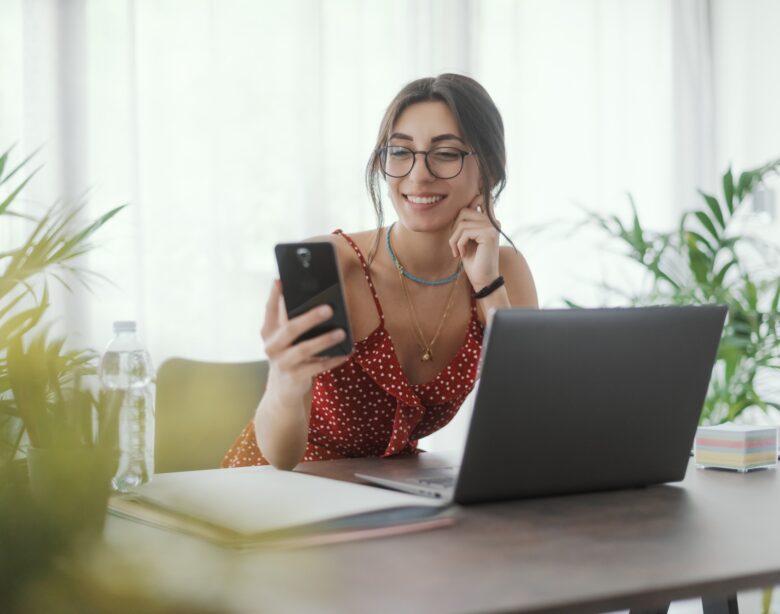 Young woman sitting at desk and using her smartphone