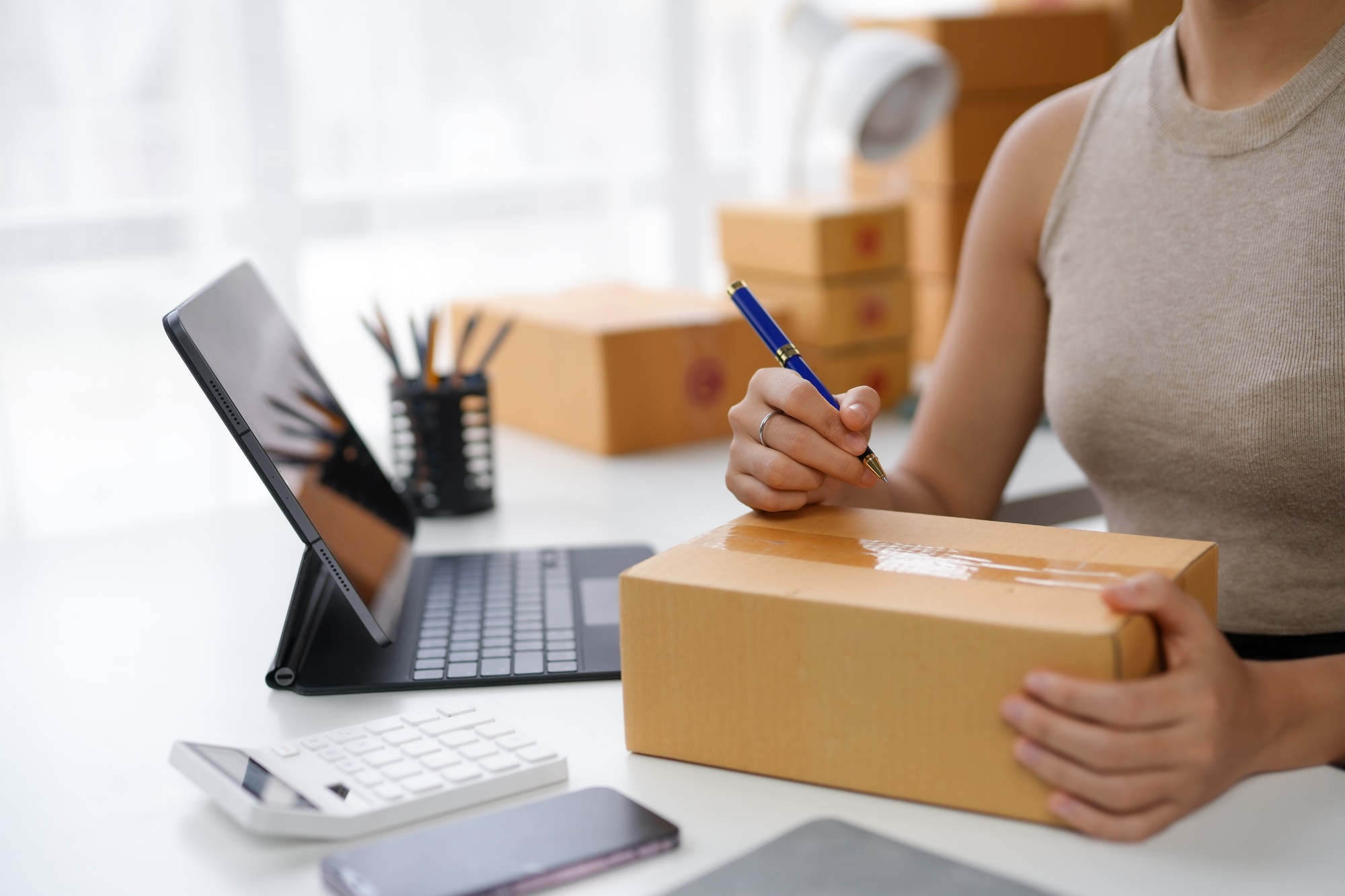 Close-up of a person preparing a package for shipping with a laptop