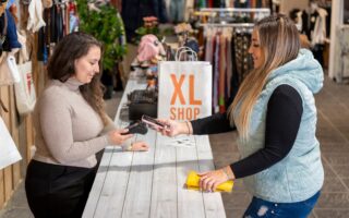Counter with a customer paying with a smartphone in a plus size clothing store